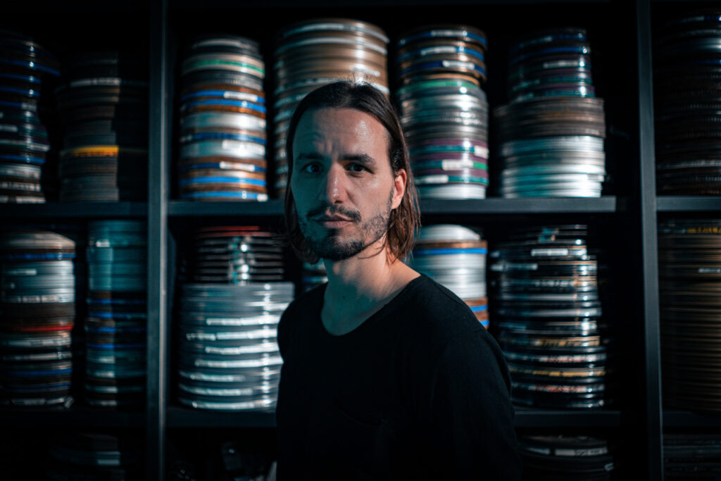 Patrick Catuz, Medienwissenschafter, Filmemacher vor einem Regal mit alten Filmrollen